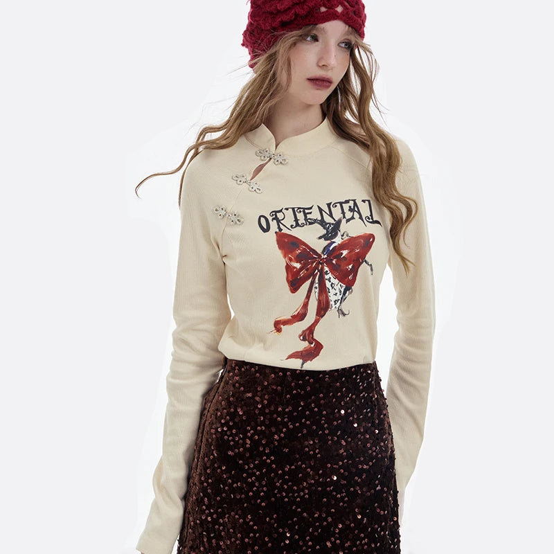 ELFSACK 2025 Winter New Arrivals Y2K Chinese Style Irregular Button Collar Bow Graphic Long Sleeve Tshirt For Women